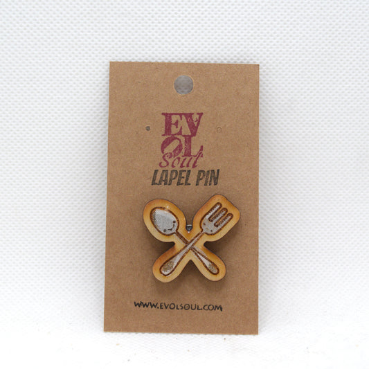 Lapel pin with crossed spoon and fork design on a brown card with 'EVOL SOUL' branding.