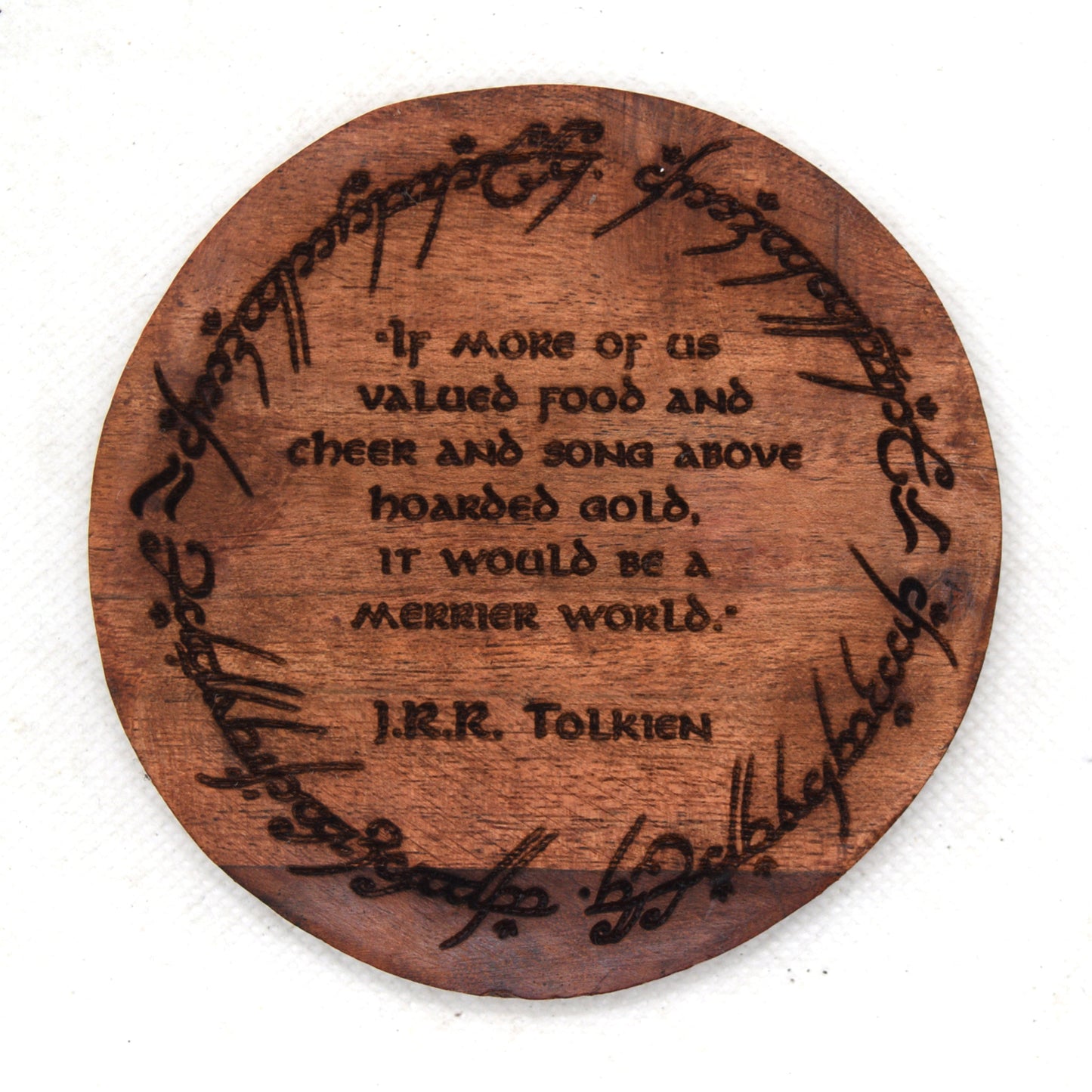 Wooden coaster with engraved J.R.R. Tolkien quote on a white background
