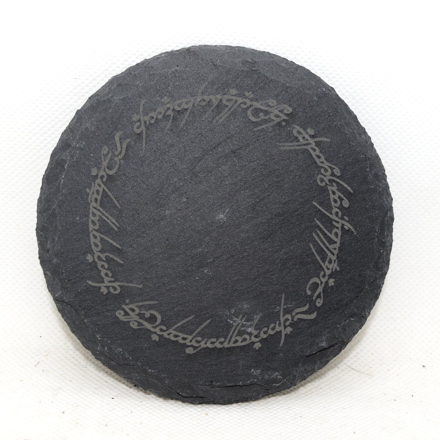 Round slate coaster with engraved quote on a white background