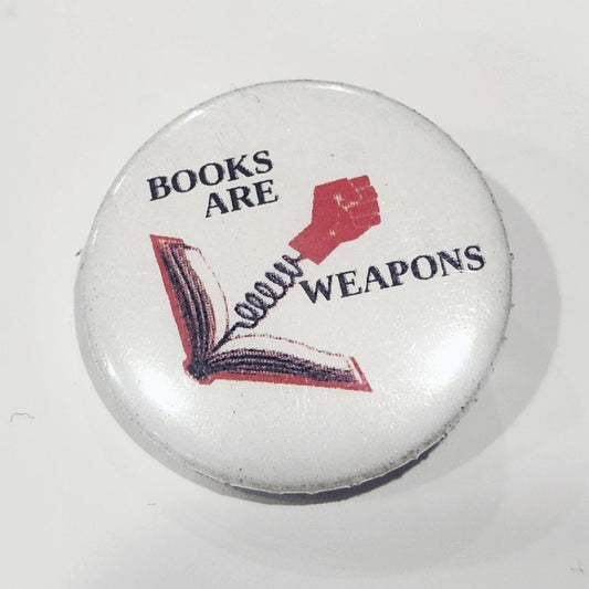 Button badge with 'Books Are Weapons' text and graphic on a white background