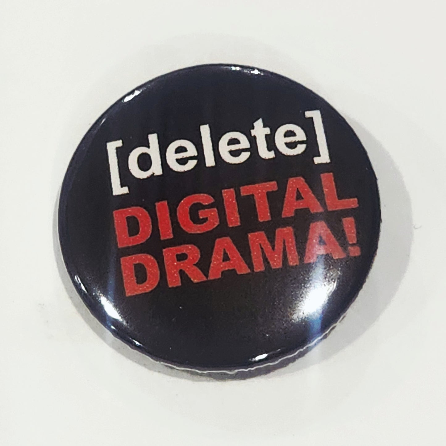 Button badge with 'delete digital drama' text on a white background