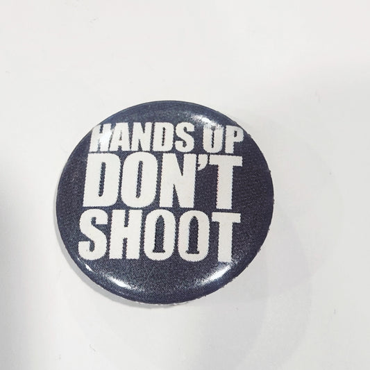 Button badge with 'HANDS UP DON'T SHOOT' text