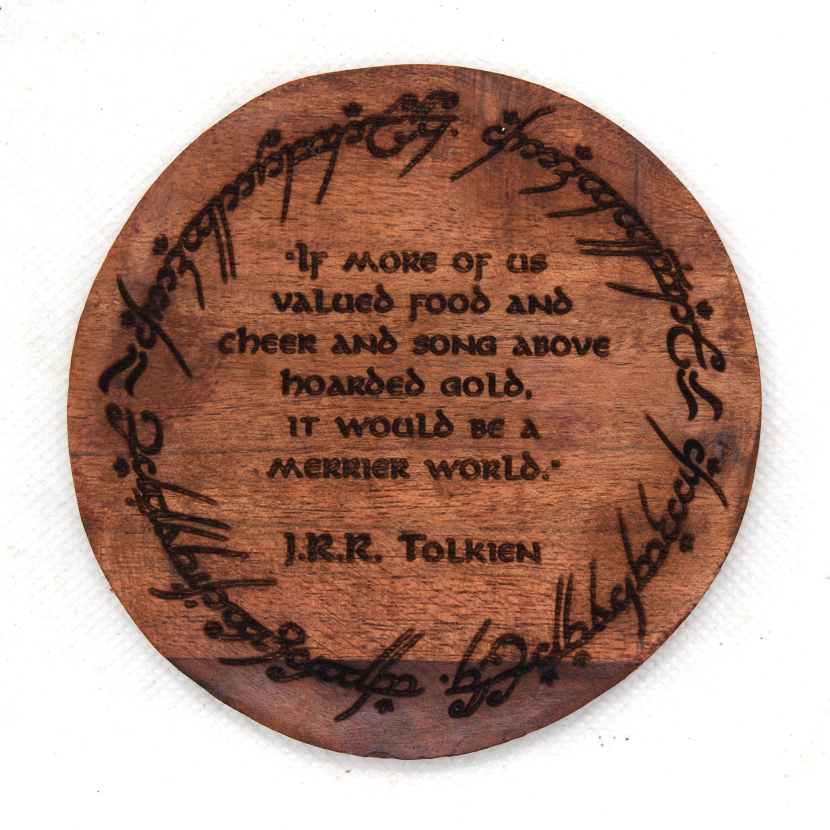 Wooden coaster with engraved J.R.R. Tolkien quote on a white background