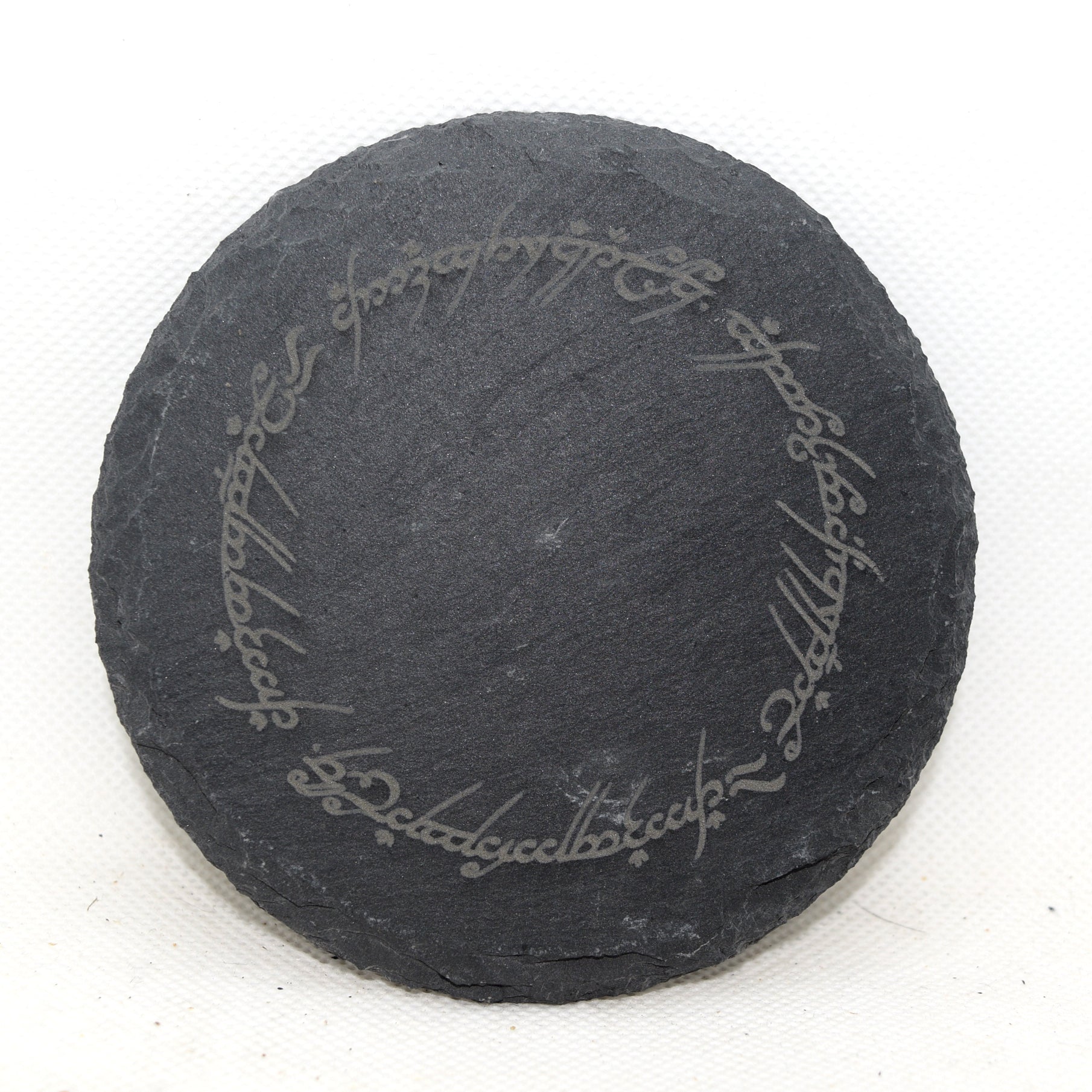 Round slate coaster with engraved  quote on a white background